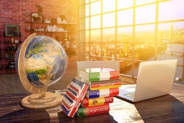 Desk with globe, books, and laptop representing multilingual travel